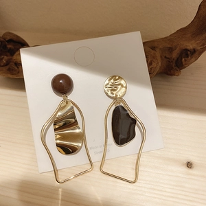 Close-up of S925 silver needle earrings with brown bead and black enamel drip on white card