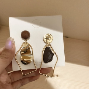 Detail of asymmetrical gold finish drop earrings with black resin and S925 silver pins