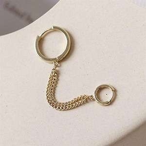 Detail of elegant gold double piercing chain earrings with two hoops on display