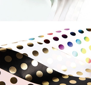 Detail of metallic gold and holographic polka dot gift wrapping paper with shiny finish
