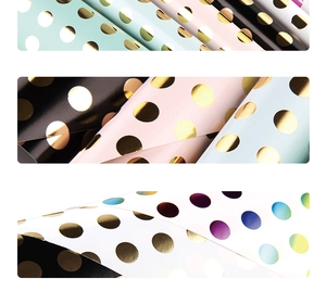 Detailed view of gift wrapping paper rolls with shiny gold polka dots and various colors
