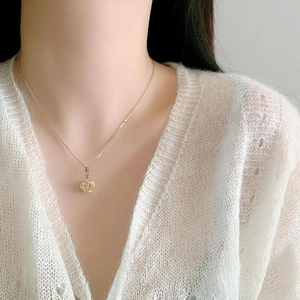 Detailed view of an elegant gold crown pendant necklace with a white pearl on a model