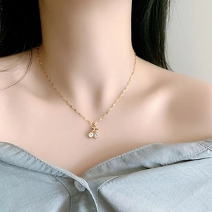 Close-up of a gold cherry necklace with sparkling zircon stones on a model's neckline