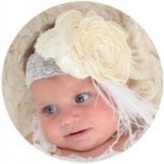 Close-up of baby lace headband featuring a cream chiffon flower and soft white feathers