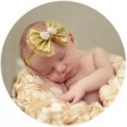 Close-up of baby lace headband with a golden bow and pearl detail on a sleeping newborn