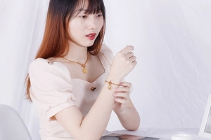 Gros plan d'un ensemble de bijoux en acier titane doré avec pendentifs ronds sur modèle
