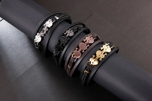 Detail of four punk skull leather bracelets in gold, rose gold, black, and silver finishes