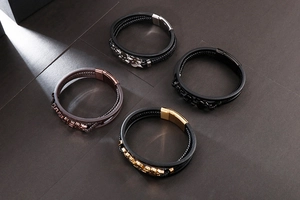 Detail of multi-layer braided leather bracelets with skull and gear metal charms