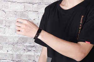Close-up of black braided leather men's bracelet with a sleek black metallic clasp