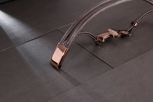 Detail of rose gold magnetic clasp and dark brown braided leather strap texture