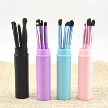 Four sets of makeup brushes in pink, blue, purple, and black with matching storage tubes