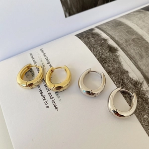 Detail of minimalist U-shaped chunky hoop earrings in polished gold and silver finishes