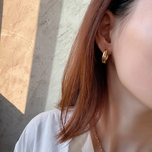 Close-up of minimalist gold geometric hoop earring on model with elegant sunlight shadows