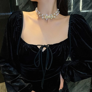 Detail of elegant double-layered pearl necklace with a diamond-studded bow on a model