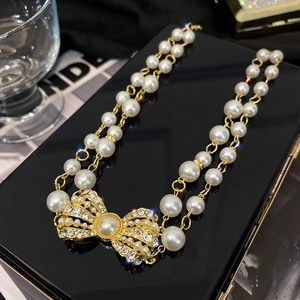 Close-up of double-layer pearl necklace with a luxury rhinestone-studded bow pendant