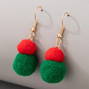 Detail shot of Christmas earrings featuring red and green pom poms with golden hooks