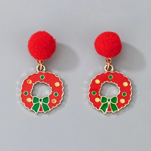 Close-up of Christmas wreath earrings with red pom-poms and green enamel bows