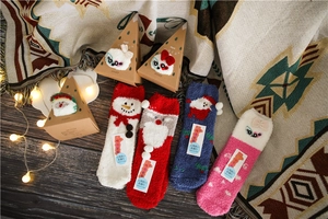 Thick coral fleece Christmas socks in a triangular gift box on a warm wooden background