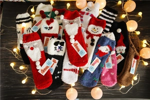 Flat lay of colorful Christmas coral fleece socks with Santa and elk patterns on wood
