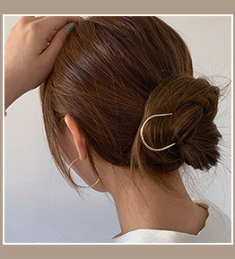 Minimalist gold U-shaped hair pin and hoop earrings set shown on a model bun