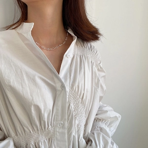 Detailed view of simple silver circle link necklace on a model wearing white shirt