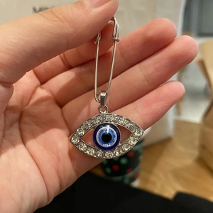 Detailed view of silver evil eye safety pin brooch with sparkling white rhinestones