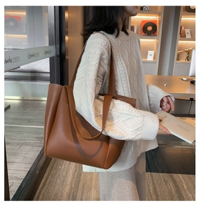 Detailed view of a large brown PU leather tote bag worn by a model in a lifestyle setting