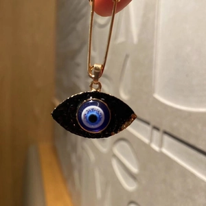 Macro shot of an Evil Eye brooch pin with blue resin and wavy golden metal edges