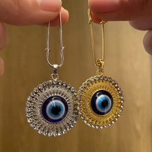 Macro view of Turkish evil eye safety pin pendants with gold and silver alloy finish