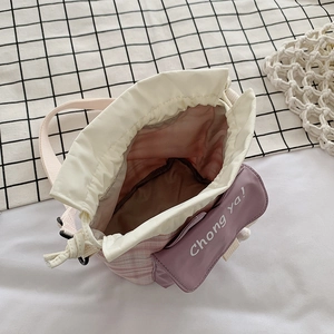 Pink corduroy bucket bag with drawstring closure and front pocket shown from a top-down view