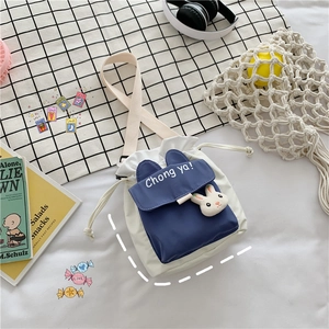 Detail of canvas drawstring bucket bag with cute rabbit plush and wide strap
