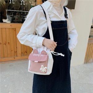 Detail of white canvas bucket bag featuring cute rabbit ears and a 3D bunny plush accessory