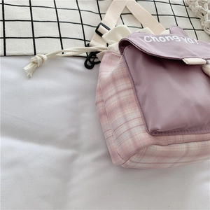 Detail of purple and pink checkered drawstring bag with white strap and text