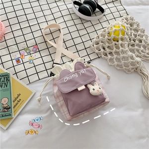 Detail of canvas drawstring bucket bag featuring purple plaid and 3D bunny ornament