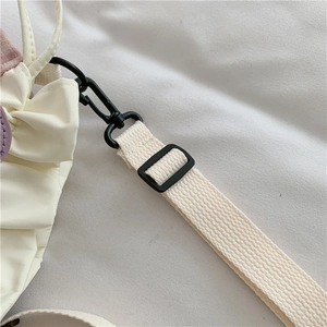 Detail of adjustable off-white canvas strap with matte black buckle and metal hook