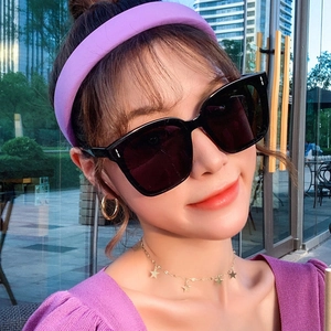 Close-up of trendy oversized black square sunglasses worn by model in a stylish urban setting