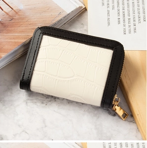Detail of compact zip card holder with white crocodile texture on marble surface