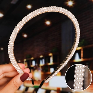 Detail showing three rows of white pearls on a gold frame with black comfort tips