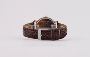 Detail view of brown crocodile leather strap and rose gold clasp of the quartz watch