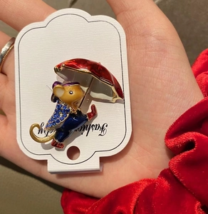 Detail of cute mouse brooch with blue rhinestones and red umbrella on white display card