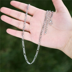 Close-up of a silver Figaro chain necklace with a lobster clasp held in hand