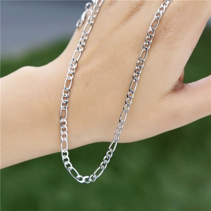 Close-up of a polished silver Figaro chain bracelet worn on a wrist against nature background