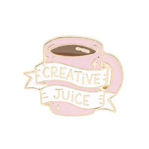 Macro-opname van een roze emaille pin met creative juice tekst en gouden metalen accenten