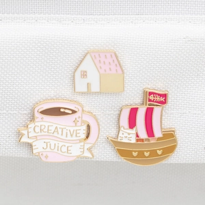 Macrodetail van emaille speldjes met roze koffiekopje, huis en piraatkattenboot