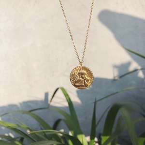 Close-up of a gold-plated medallion pendant featuring a classic cherub angel relief
