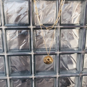 Macro view of gold-plated double-layer chain necklace with embossed cherub angel pendant