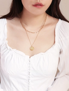 Close-up of a layered gold Cupid angel pendant necklace on a paperclip chain