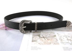 Detailed view of vintage floral carvings on silver buckle and tip of black PU leather belt