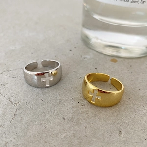 Detail of hollow cross open rings in silver and gold finishes on a textured gray surface