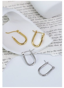Polished gold and silver U-shaped hoop earrings displayed on a minimalist background